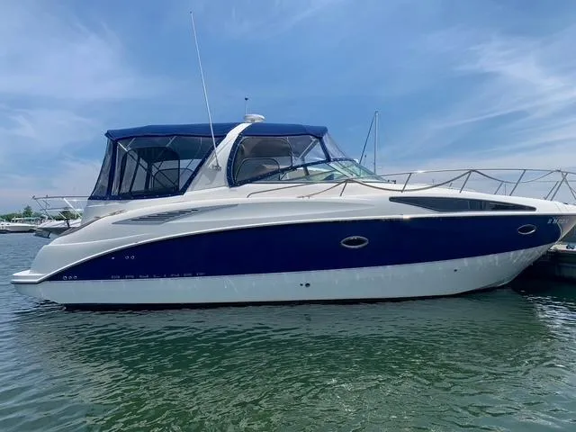 The Image of 2007 Bayliner 325 boat docked on calm water under a clear blue sky. - 0