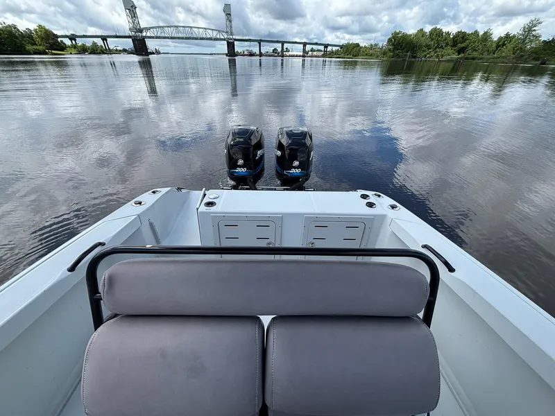 Slide: The Image of 2004 Baja 250 Sportfish boat with dual engines on a calm river, bridge in background. - 13