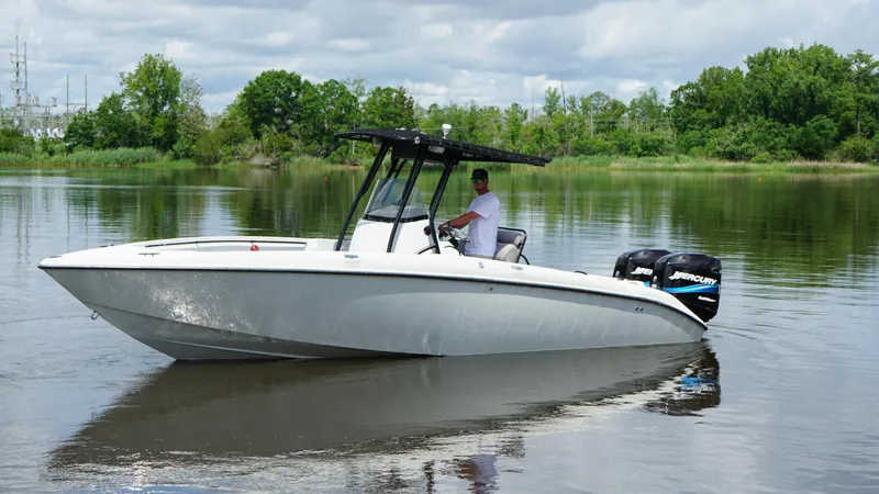 Slide: The Image of 2004 Baja 250 Sportfish boat on calm water, with lush green trees in the background. - 17