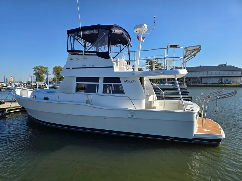 The Image of 1997 Mainship 350 Trawler docked in a marina under clear blue skies. - 0