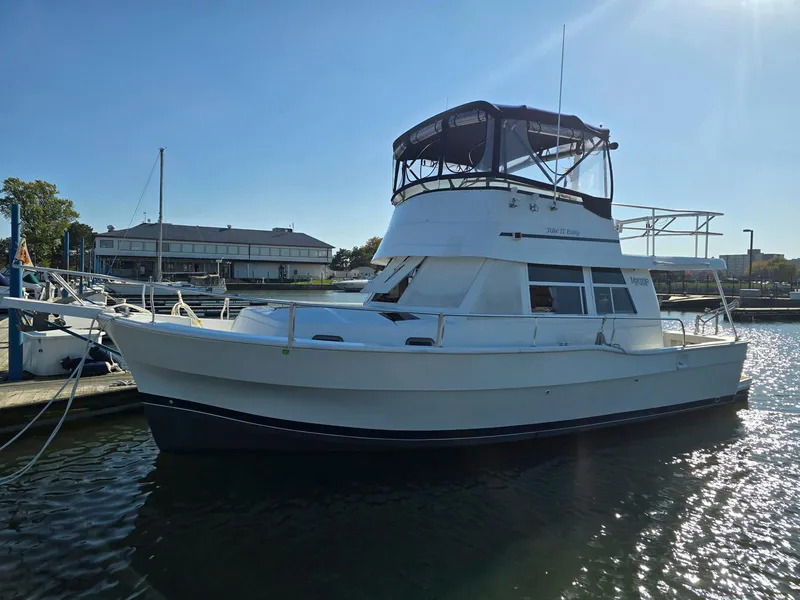 Slide: The Image of 1997 Mainship 350 Trawler docked on calm water under clear blue sky. - 3