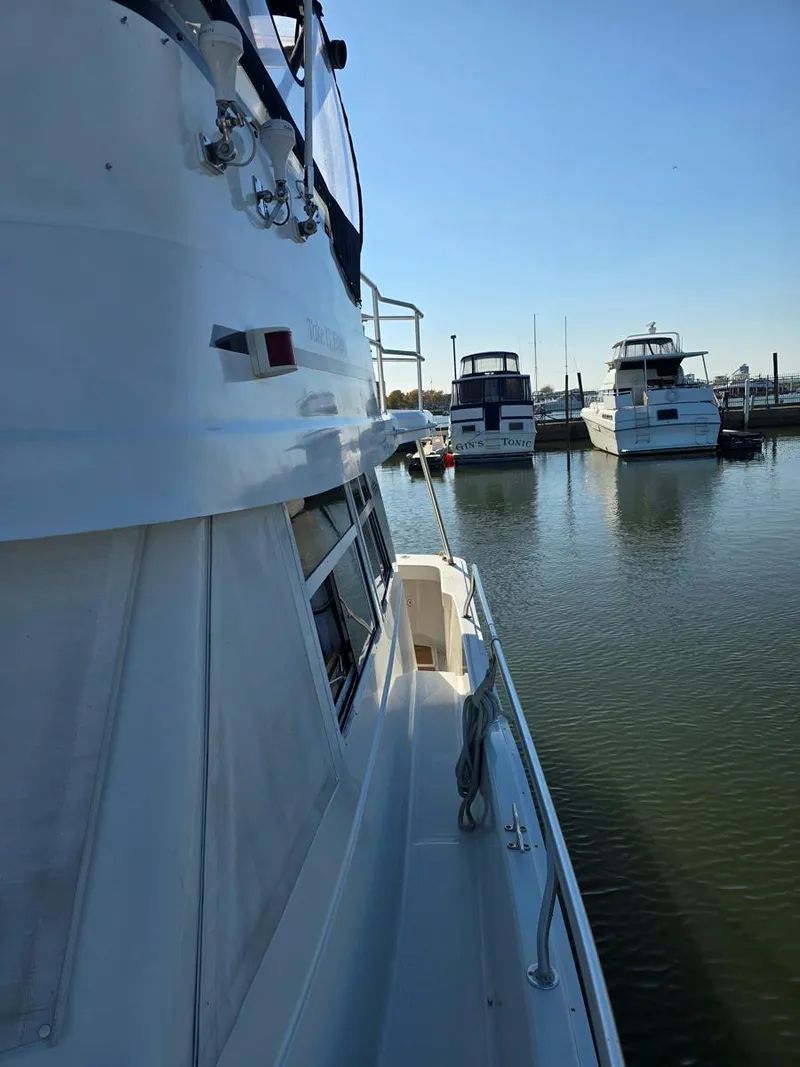 Slide: The Image of 1997 Mainship 350 Trawler on calm water, sunny day, person on deck. - 5