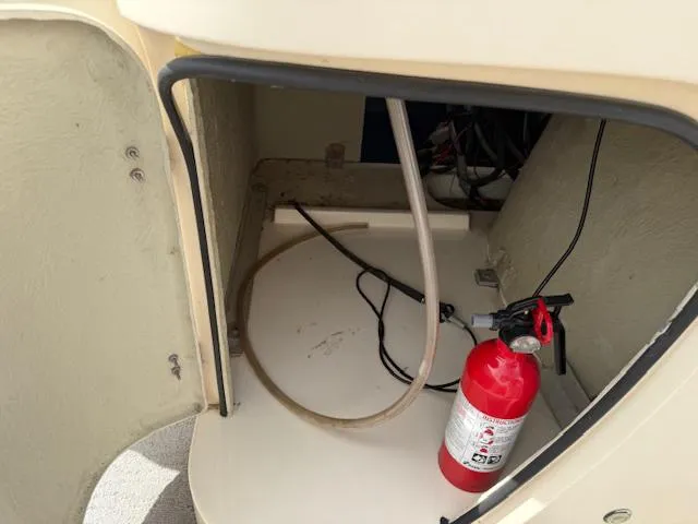 Slide: The Image of Open storage compartment on 2014 Godfrey 22 Aqua Patio boat with fire extinguisher and cables. - 14