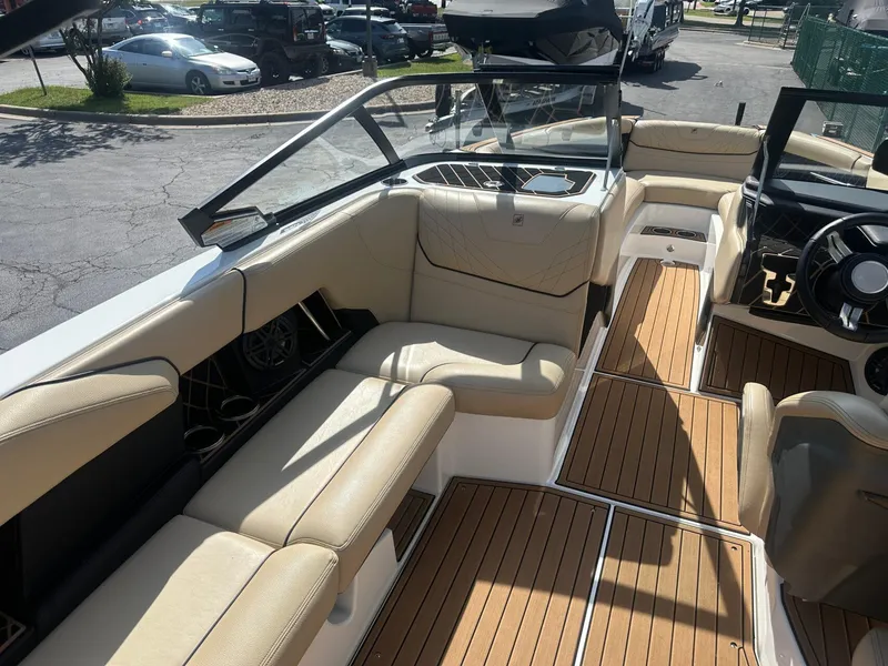 Slide: The Image of 2020 Nautique GS24 boat interior with beige seating and wood flooring. - 11