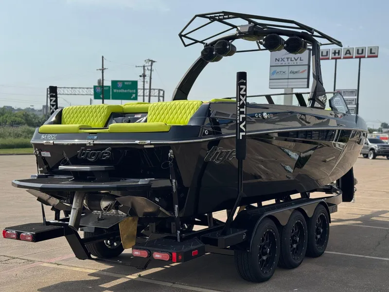 Slide: The Image of 2025 Tigé 24RZX boat with lime green accents on a trailer in a parking lot. - 5