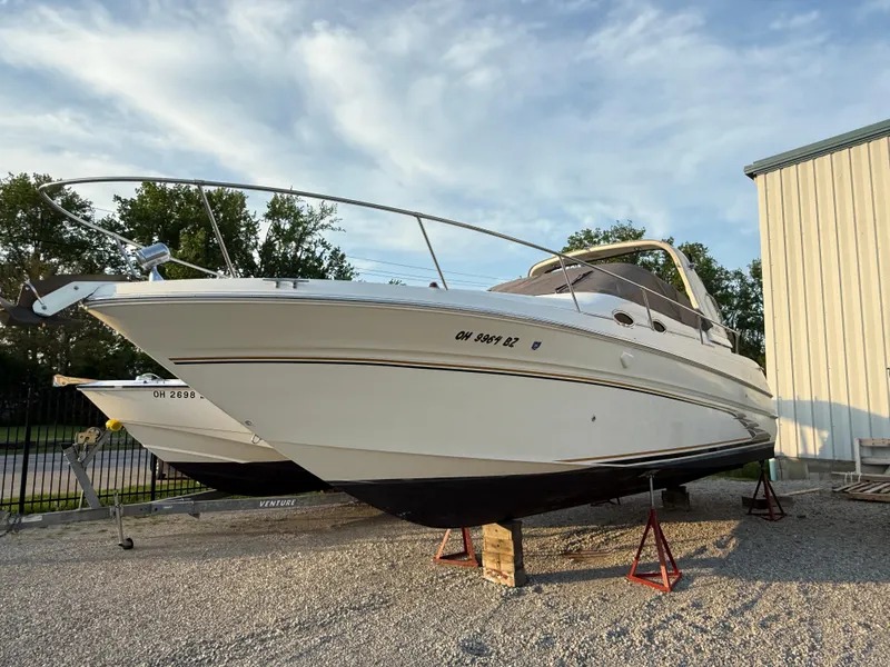Slide: The Image of 1997 Sea Ray 290 Sundancer boat on stands, parked outdoors. - 1