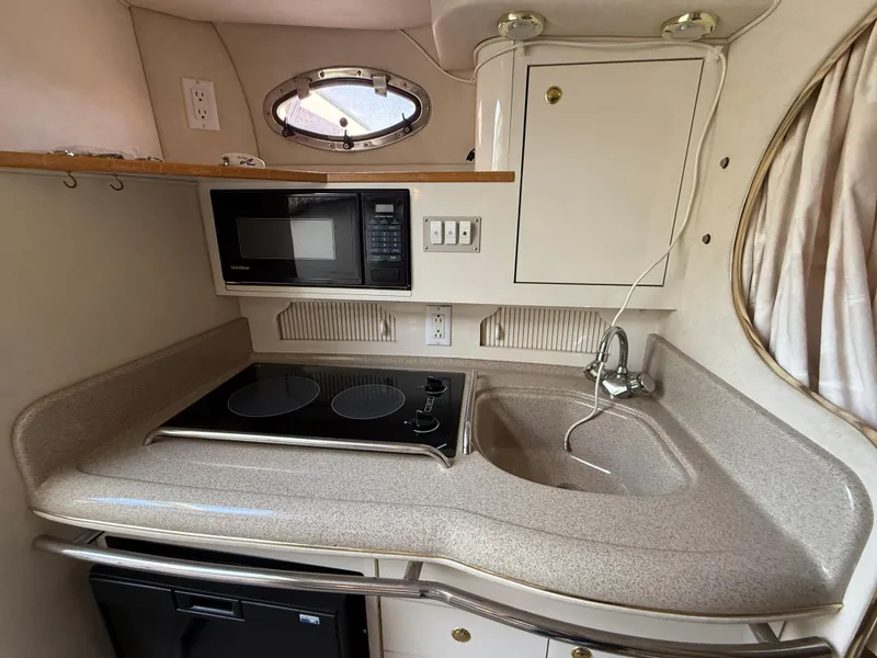 Slide: The Image of 1997 Sea Ray 290 Sundancer kitchen with stove, microwave, sink, and storage cabinets. - 10