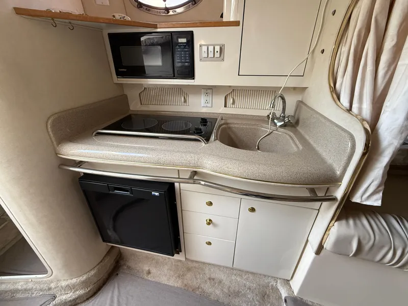 Slide: The Image of 1997 Sea Ray 290 Sundancer galley with sink, stove, microwave, and mini-fridge. - 11