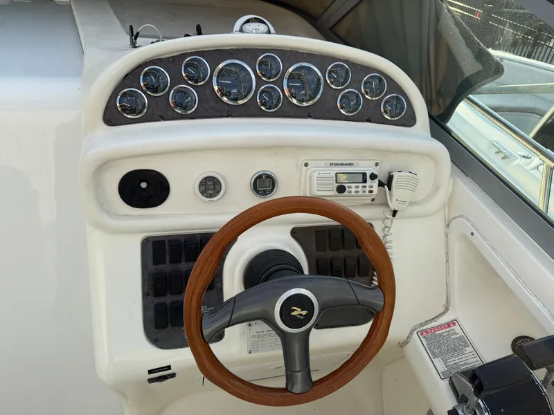 Slide: The Image of 1997 Sea Ray 290 Sundancer helm with gauges and wood-trimmed steering wheel. - 19