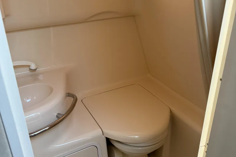 Slide: The Image of 1997 Sea Ray 290 Sundancer bathroom with sink and toilet, compact marine design. - 24