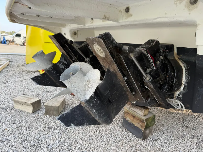 Slide: The Image of 1997 Sea Ray 290 Sundancer boat propellers on gravel, supported by wooden blocks. - 5