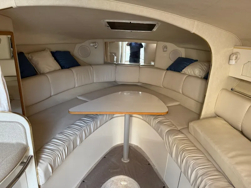 Slide: The Image of Interior of 1997 Sea Ray 290 Sundancer boat with white seating and table. - 8