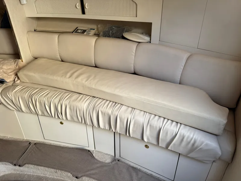 Slide: The Image of Interior seating of 1997 Sea Ray 290 Sundancer boat, featuring beige cushions and storage cabinets. - 9