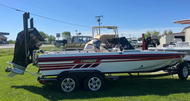 Slide: The Image of 2022 Charger VMAG 2010 boat with red stripes on a trailer, parked on grass. - 13