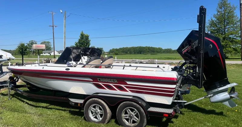 Slide: The Image of Charger VMAG 2010 boat on trailer, 2022 model, parked on grass under clear blue sky. - 2
