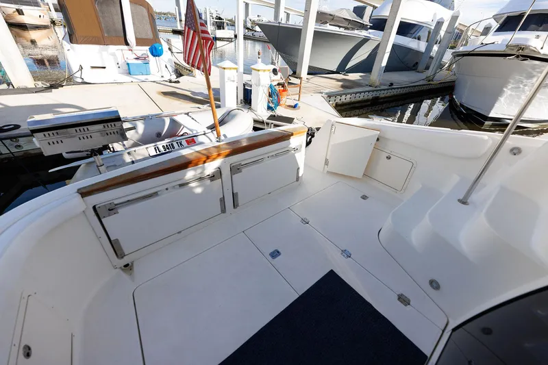 Slide: The Image of 2003 Regal Commodore 3880 yacht deck at marina, featuring storage compartments and American flag. - 31