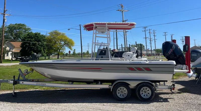 Slide: The Image of 2023 Charger 2230 L Sport boat on trailer, parked outdoors under clear blue sky. - 12