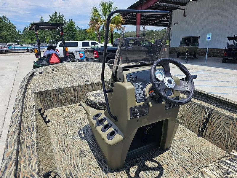 Slide: The Image of 2025 Tracker Grizzly 1860 CC boat with camouflage design, parked outdoors near a building. - 10