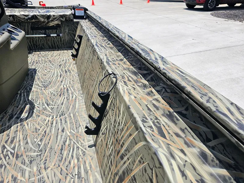 Slide: The Image of 2025 Tracker Grizzly 1860 CC boat interior with camouflage design and rod holders. - 15