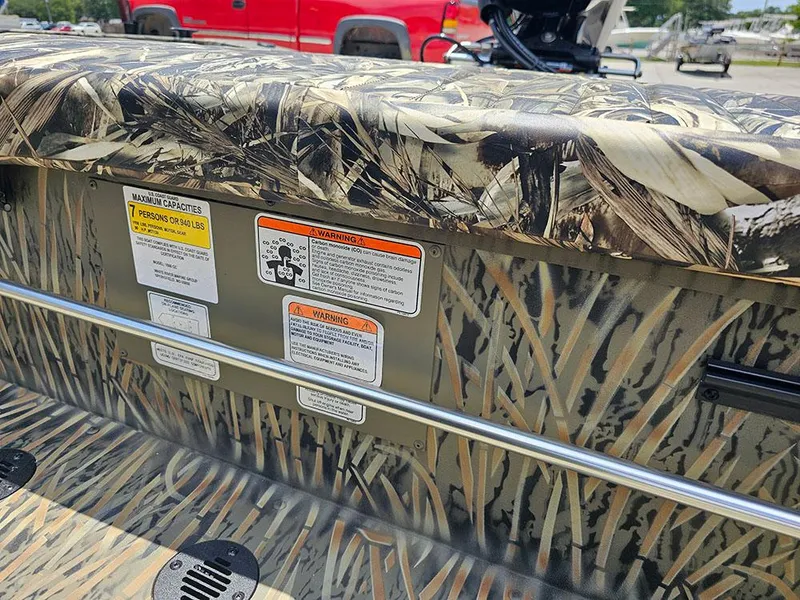Slide: The Image of 2025 Tracker Grizzly 1860 CC boat with camouflage design and safety labels. - 16
