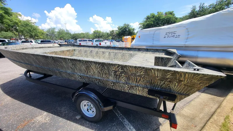 The Image of 2025 Tracker Grizzly 2072 Utility boat on trailer, camo design, parked outdoors. - 0