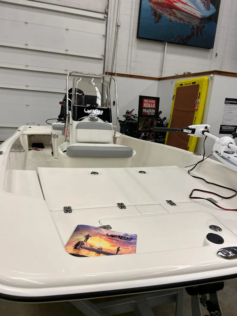 Slide: The Image of 2025 Mako Pro Skiff 15 CC boat in showroom, featuring sleek design and modern equipment. - 2