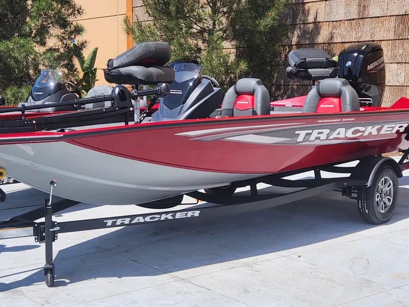 The Image of 2025 Tracker Pro Team 175 boat, red and gray, on trailer, parked outdoors. - 0