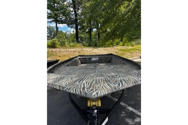 Slide: The Image of 2025 Tracker Grizzly 1860 Utility boat with camouflage pattern, parked outdoors. - 2
