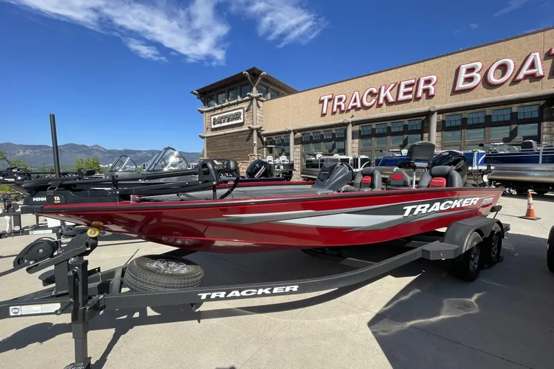The Image of 2025 Tracker Savage 215 boat displayed at dealership with mountains in background. - 0