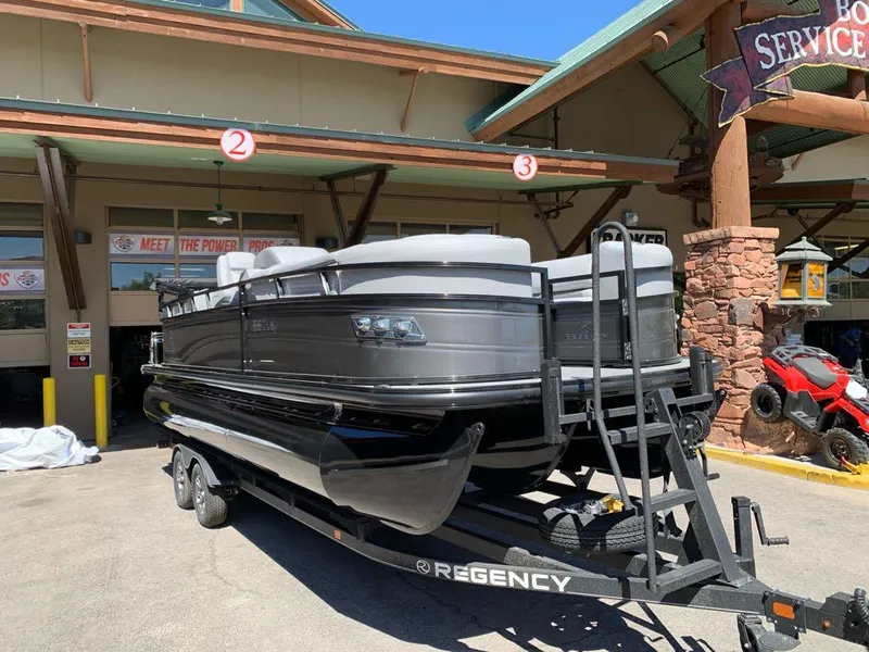 Slide: The Image of 2025 Regency 230 LE3 pontoon boat on trailer outside service center. - 3