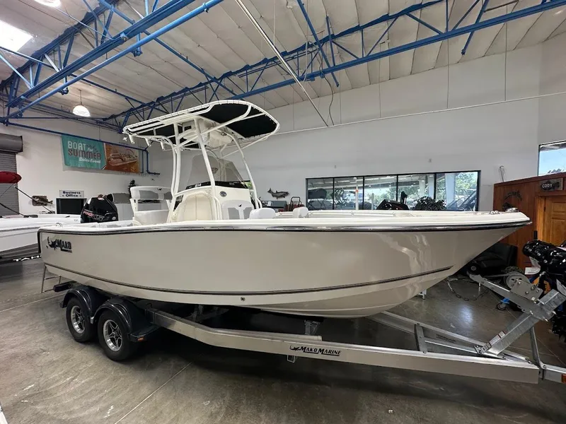 The Image of 2025 Mako 214 CC boat on trailer in showroom, featuring sleek design and modern build. - 0