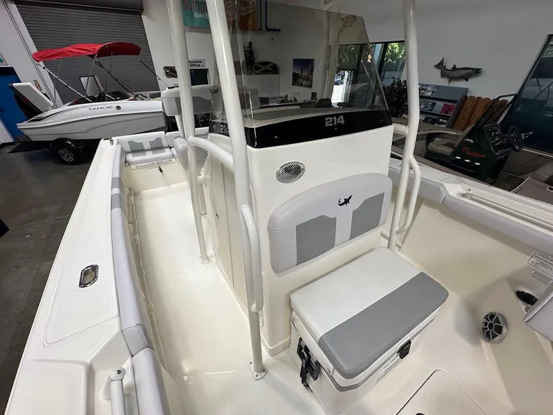 Slide: The Image of 2025 Mako 214 CC boat interior with seating and storage, displayed in a showroom. - 14