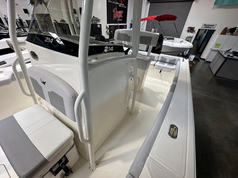 Slide: The Image of 2025 Mako 214 CC boat interior with seating and console, displayed in showroom. - 18
