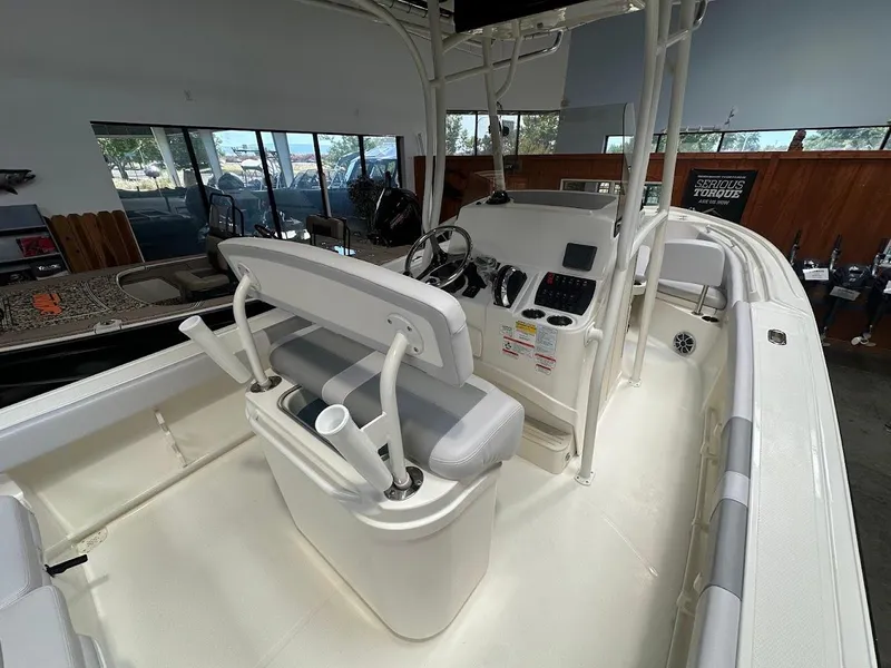 Slide: The Image of 2025 Mako 214 CC boat interior with helm, seating, and controls in showroom. - 9