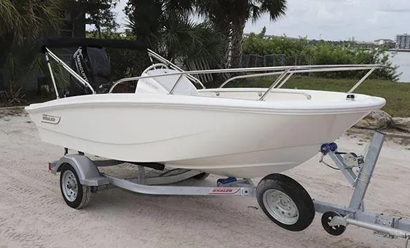 Slide: The Image of 2025 Boston Whaler 130 SUPERSPORT boat on trailer, parked on sandy ground. - 10