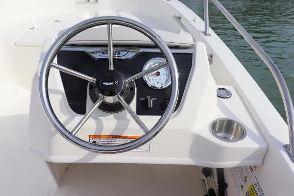 Slide: The Image of 2025 Boston Whaler 130 SuperSport steering console with stainless steel wheel and gauge. - 3