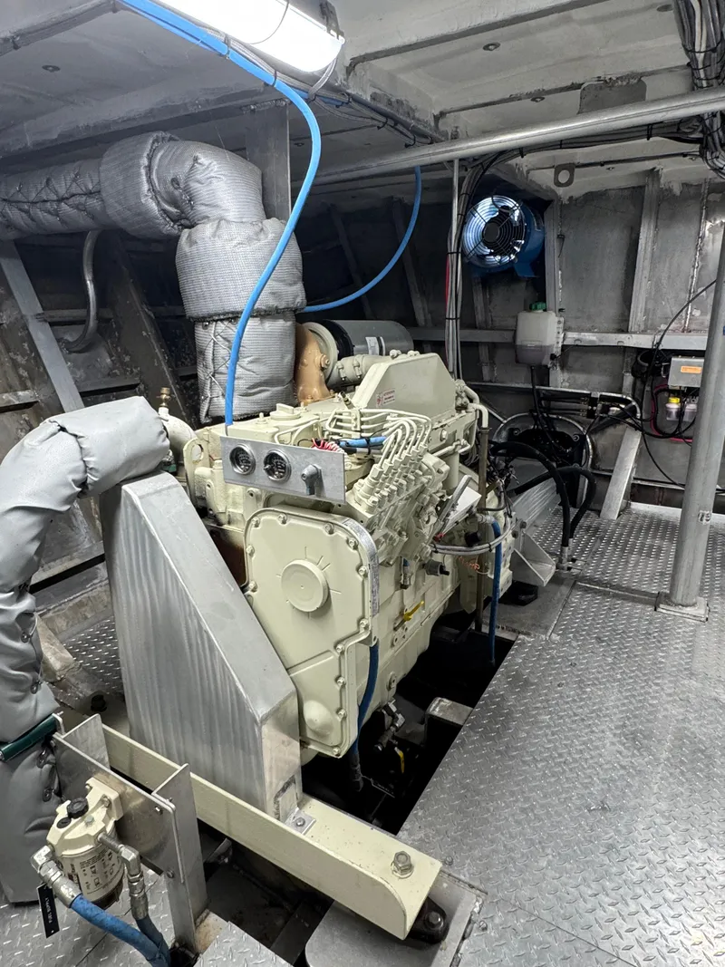 Slide: The Image of Engine room of a 1985 custom house boat, featuring a well-maintained engine and metallic flooring. - 14