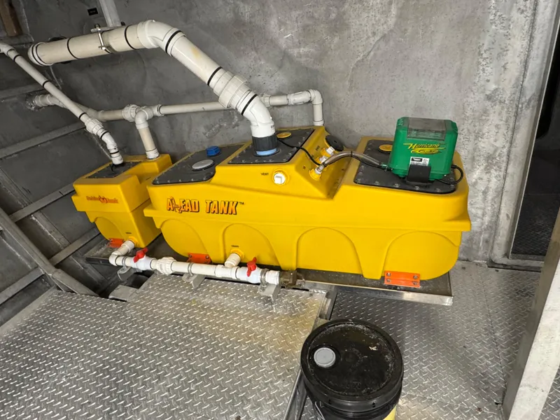 Slide: The Image of Yellow waste tank system on a 1985 custom houseboat, featuring pipes and a green component. - 15