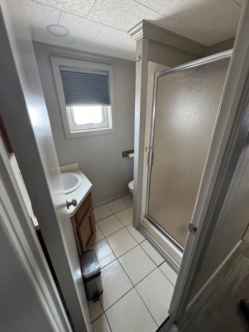 Slide: The Image of Compact bathroom in a 1985 custom houseboat with shower, sink, and window. - 30