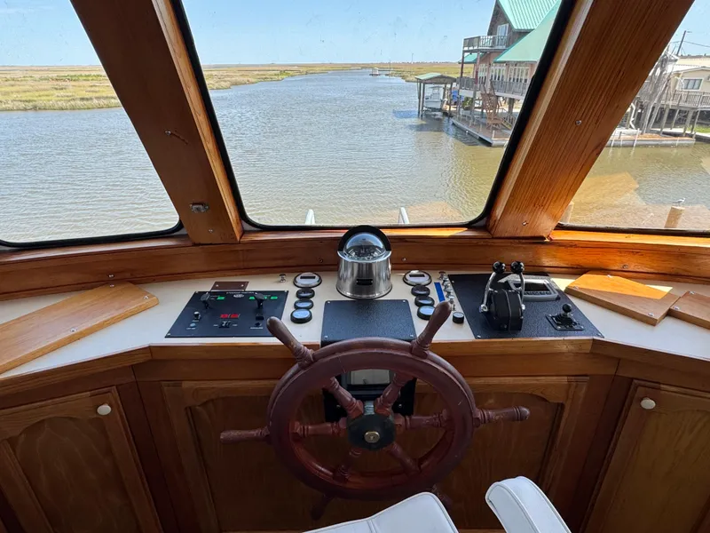 Slide: The Image of Pilot's view from a 1985 custom houseboat, featuring a wooden steering wheel and control panel. - 34
