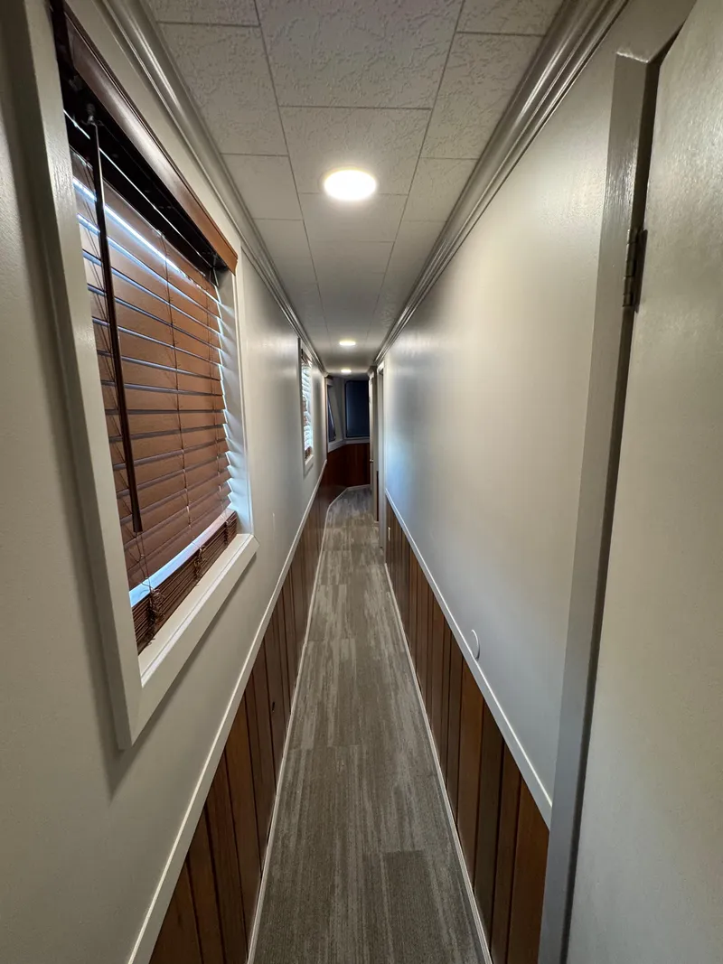 Slide: The Image of Narrow hallway inside a 1985 custom houseboat with wood paneling and window blinds. - 47