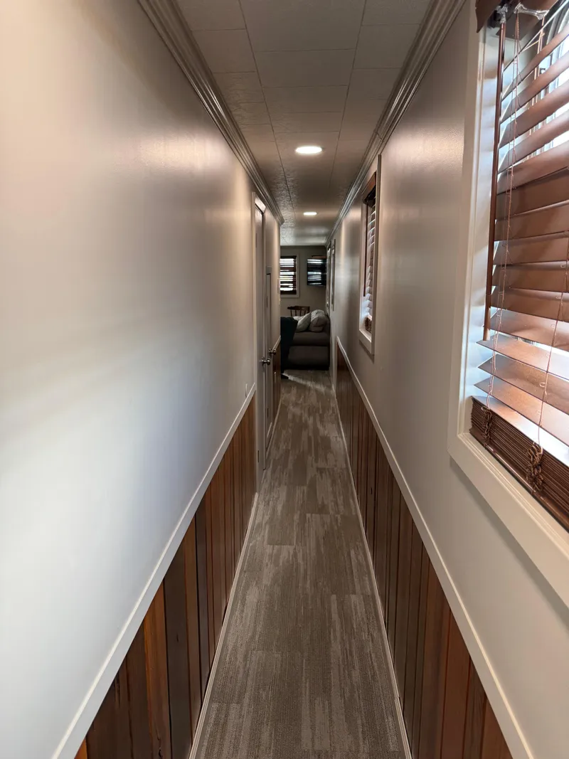 Slide: The Image of Narrow hallway inside a 1985 custom houseboat with wood paneling and modern decor. - 7