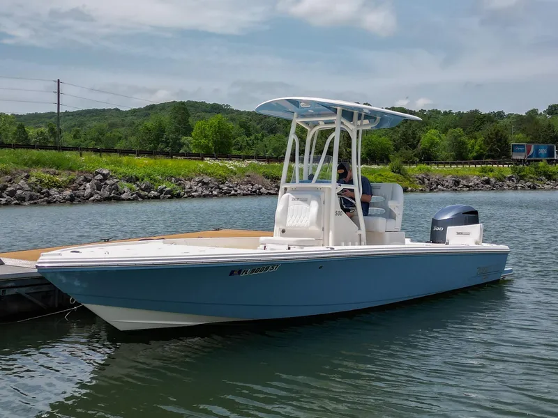 Slide: The Image of 2021 Pathfinder 2500 Hybrid boat on a lake with lush green trees in the background. - 1