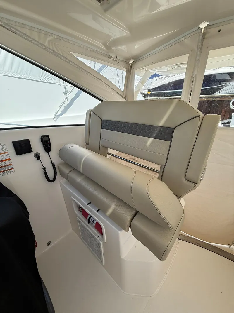 Slide: The Image of 2018 Pursuit DC 365 Dual Console boat interior with beige seating and control panel. - 14