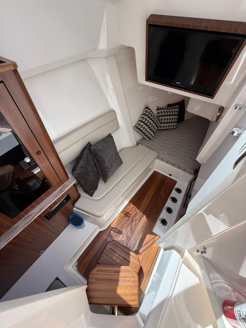 Slide: The Image of 2018 Pursuit DC 365 Dual Console interior with seating, TV, and wooden accents. - 19