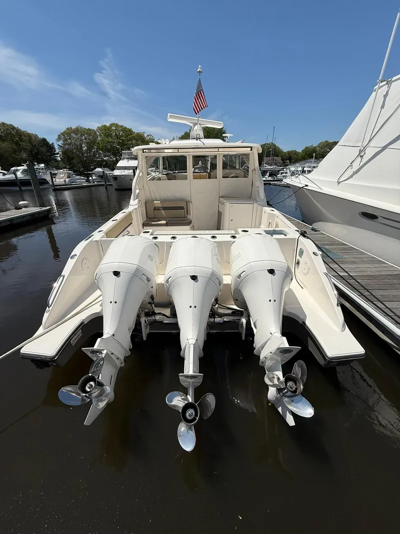 Slide: The Image of 2018 Pursuit DC 365 Dual Console boat with triple outboard engines docked in marina. - 2