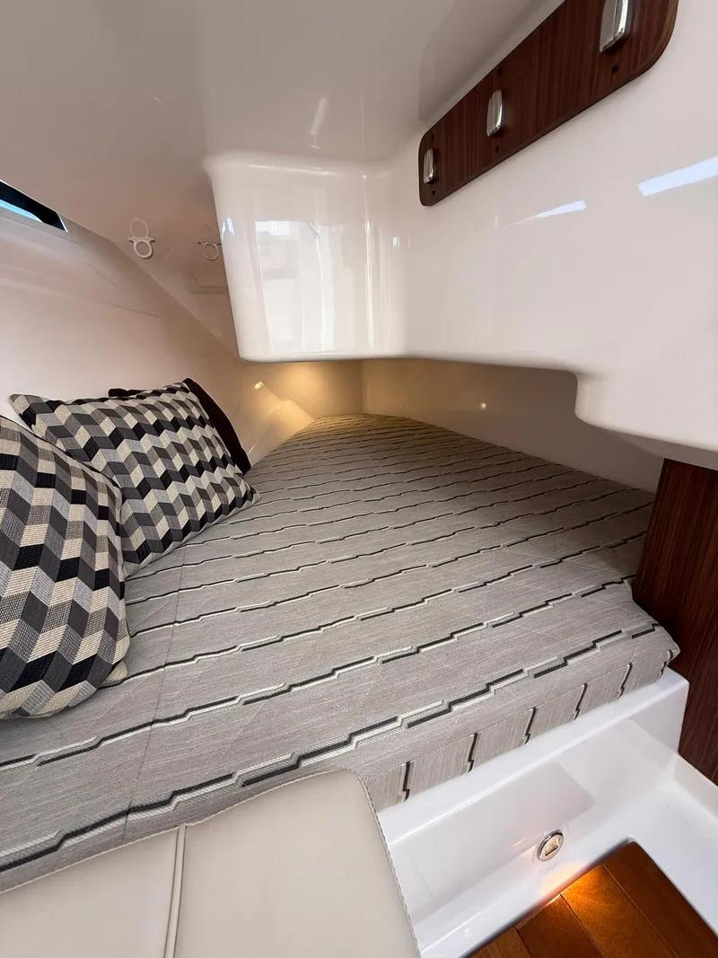 Slide: The Image of 2018 Pursuit DC 365 Dual Console cabin with striped bedding and checkered pillows. - 24