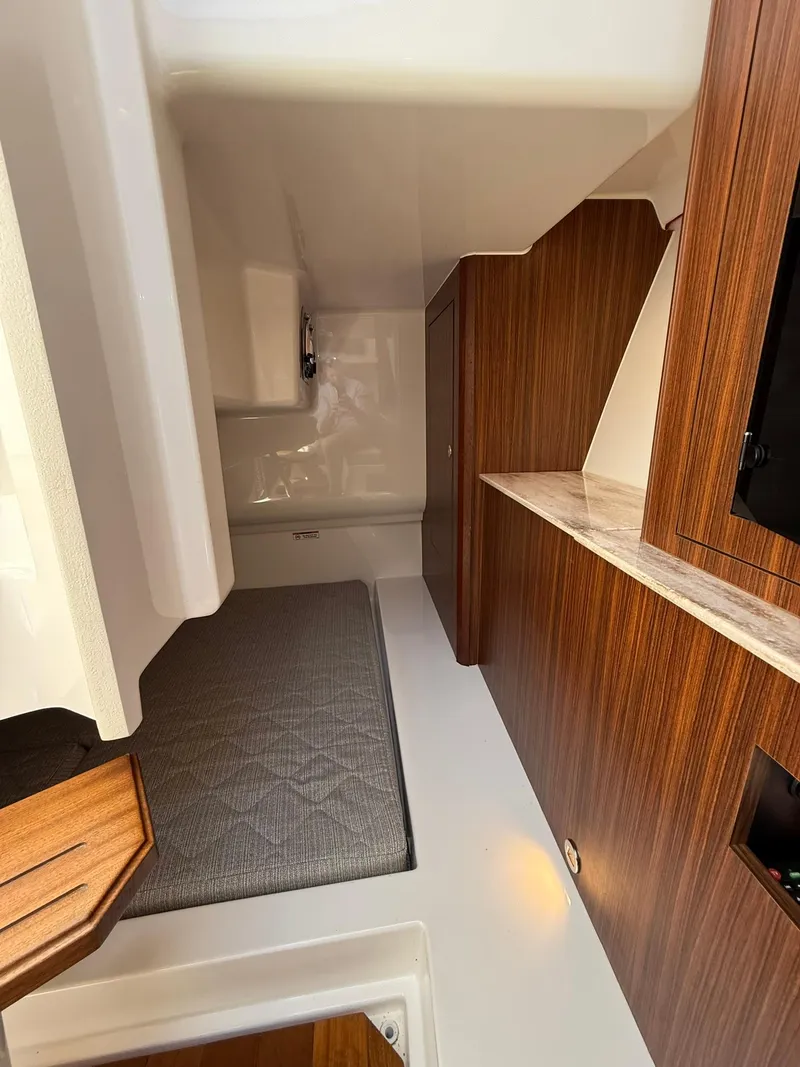 Slide: The Image of 2018 Pursuit DC 365 Dual Console cabin interior with wood accents and cushioned seating. - 25