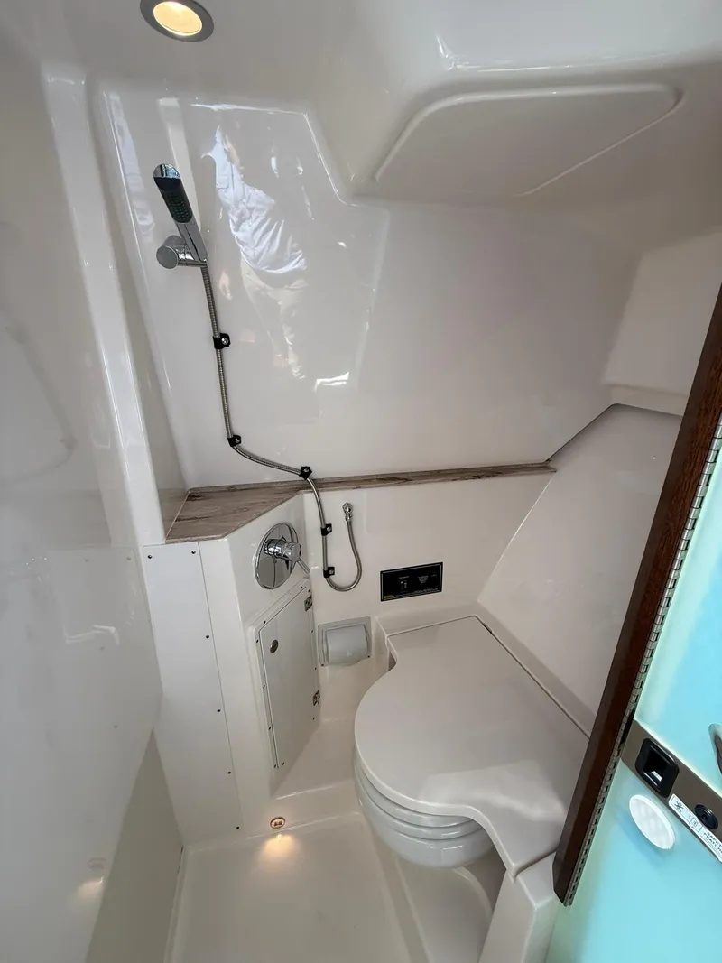 Slide: The Image of 2018 Pursuit DC 365 Dual Console boat bathroom with shower and toilet. - 32