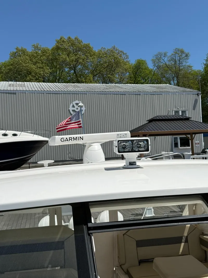 Slide: The Image of 2018 Pursuit DC 365 Dual Console with Garmin radar, docked near a metal building. - 36